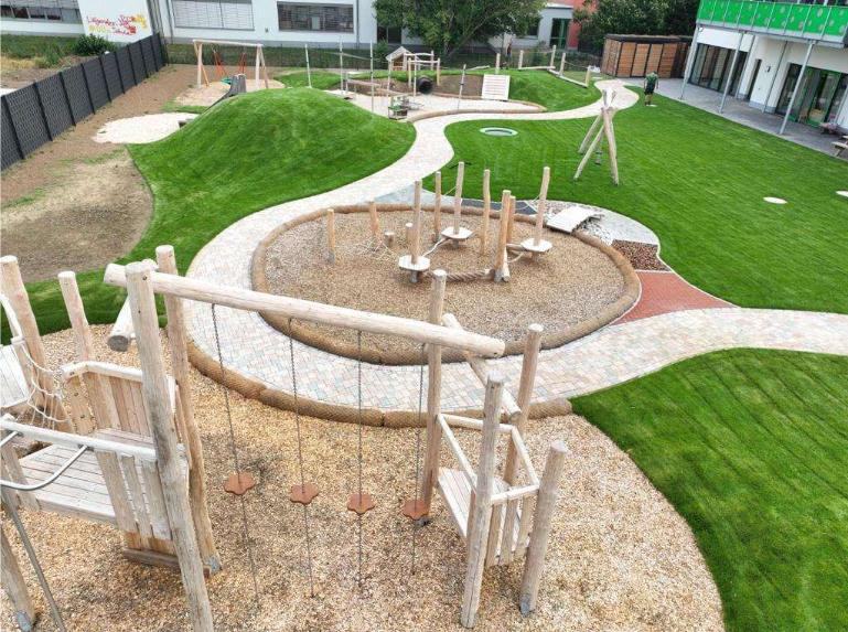 Fertige Außenanlage mit Spielgeräten, Pflasterweg und Rasen